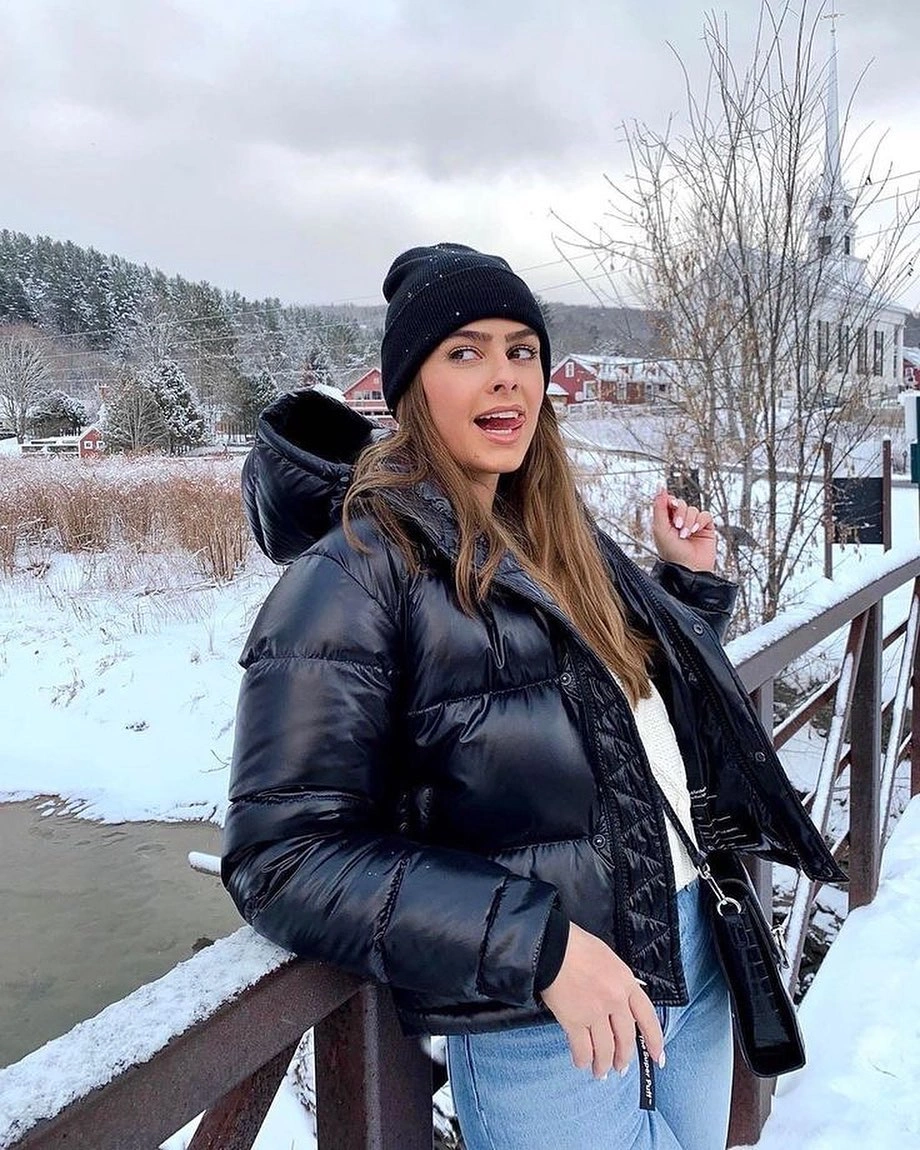 Glossy black puffer with white sweater and light jeans in snow
