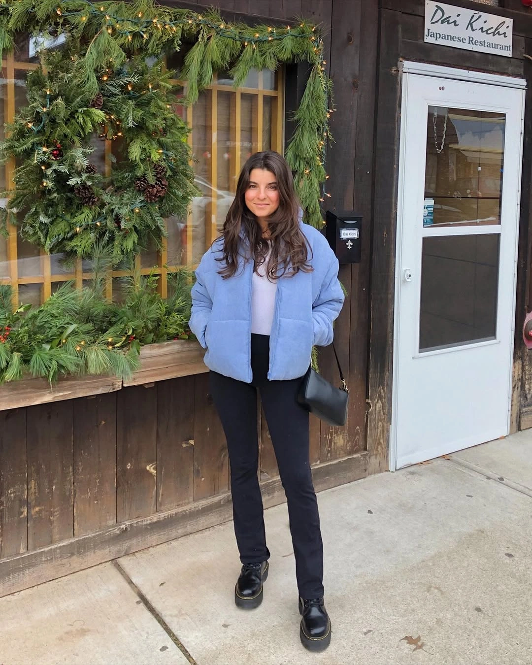 Pale blue short puffer with black pants, boots and bag
