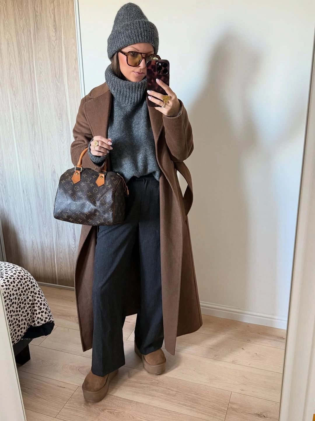 Brown long coat with gray knit beanie and dark trousers