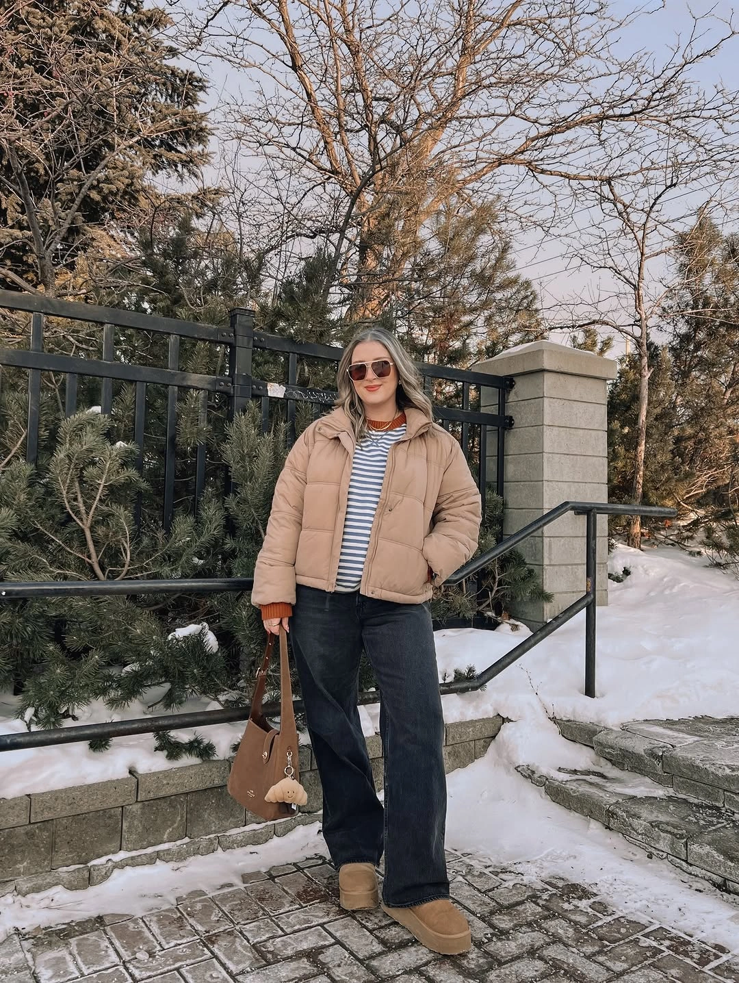 Tan puffer jacket with striped top dark jeans and boots
