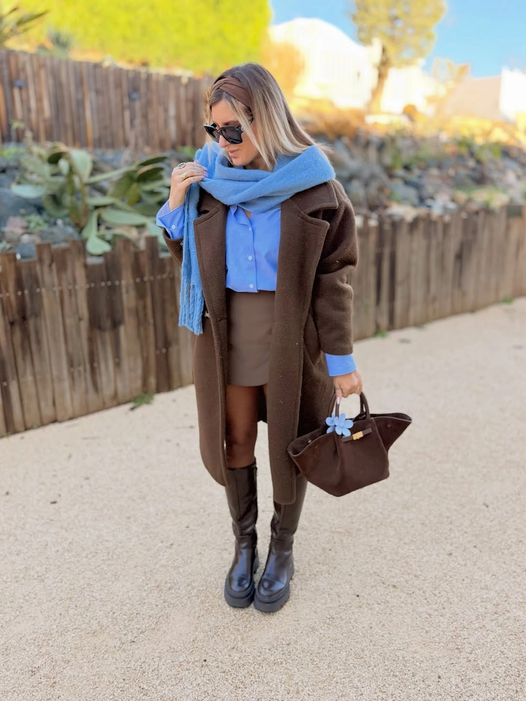 Brown long coat with bright blue scarf and tall black boots