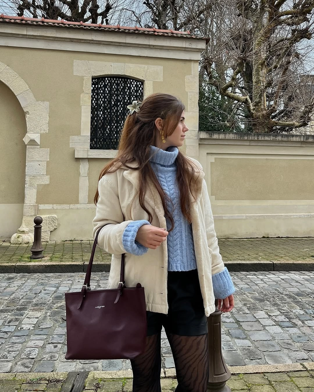 Cream jacket with blue turtleneck dark lower layer and burgundy tote