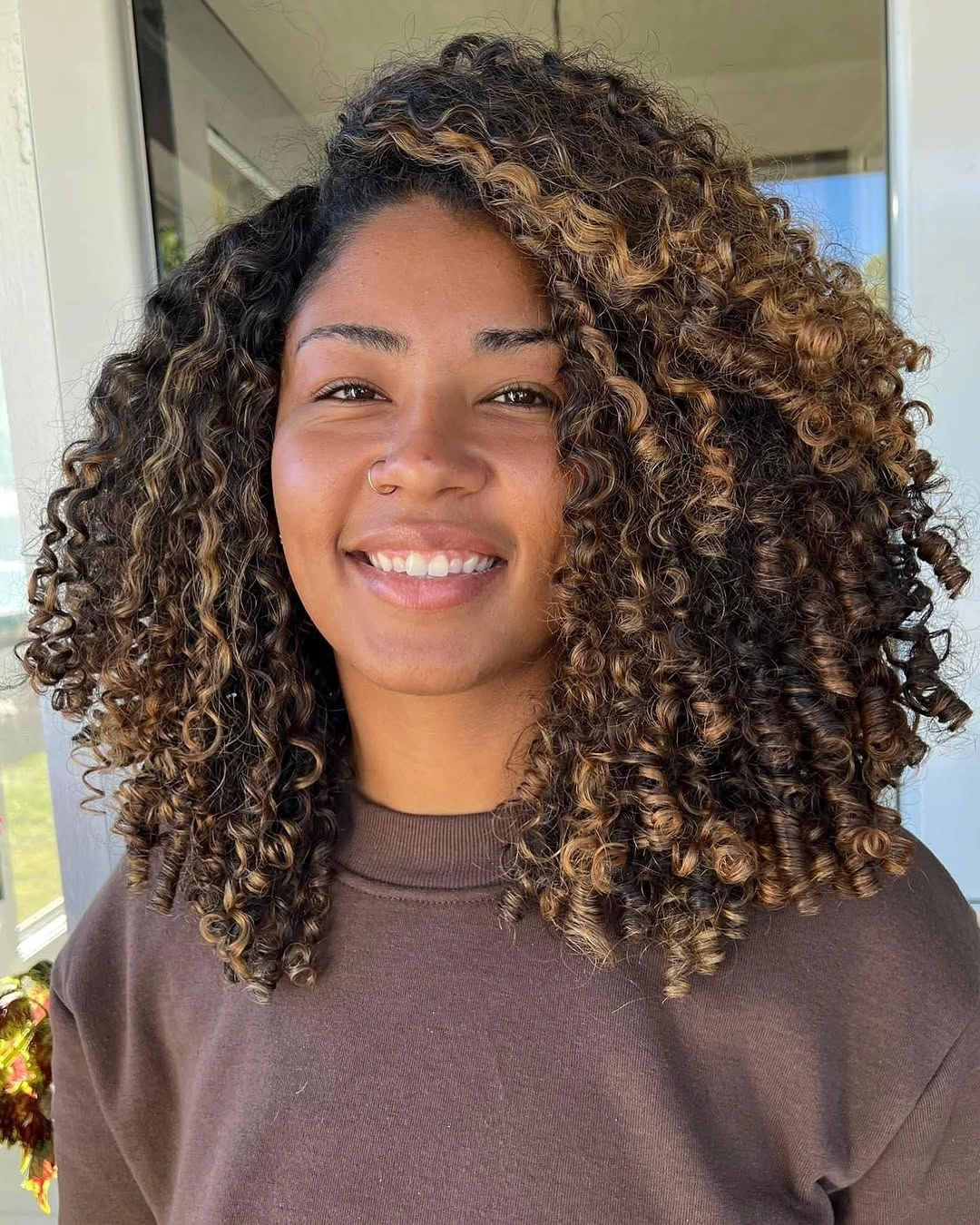 Shoulder length dark curls with golden caramel highlights