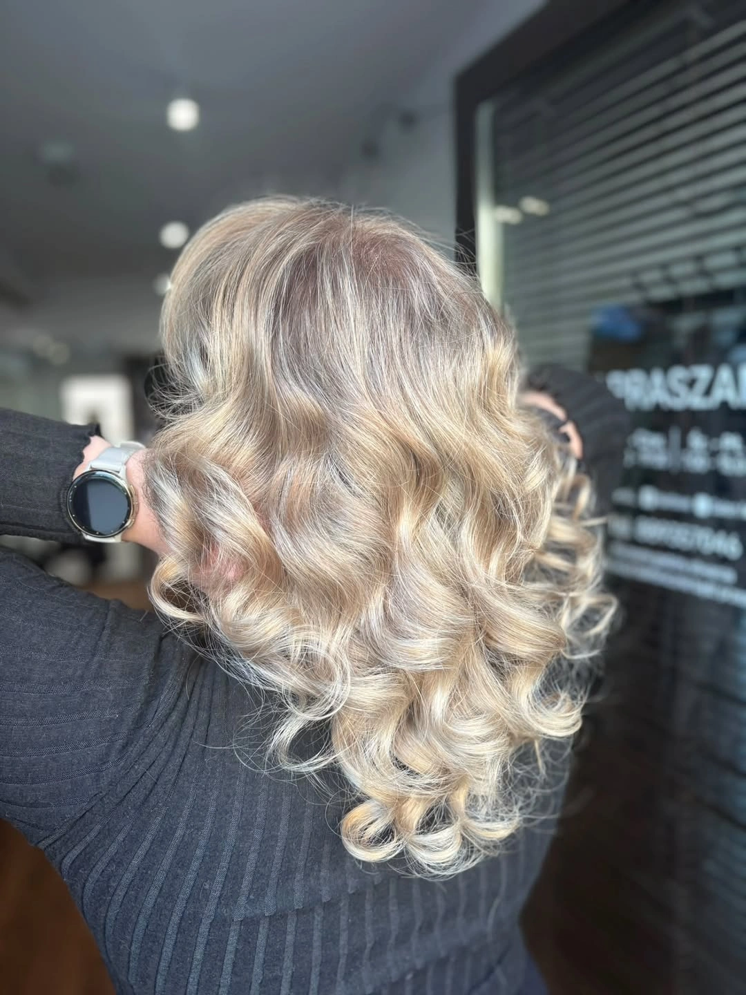 Back view of curled blonde hair with shadowed roots