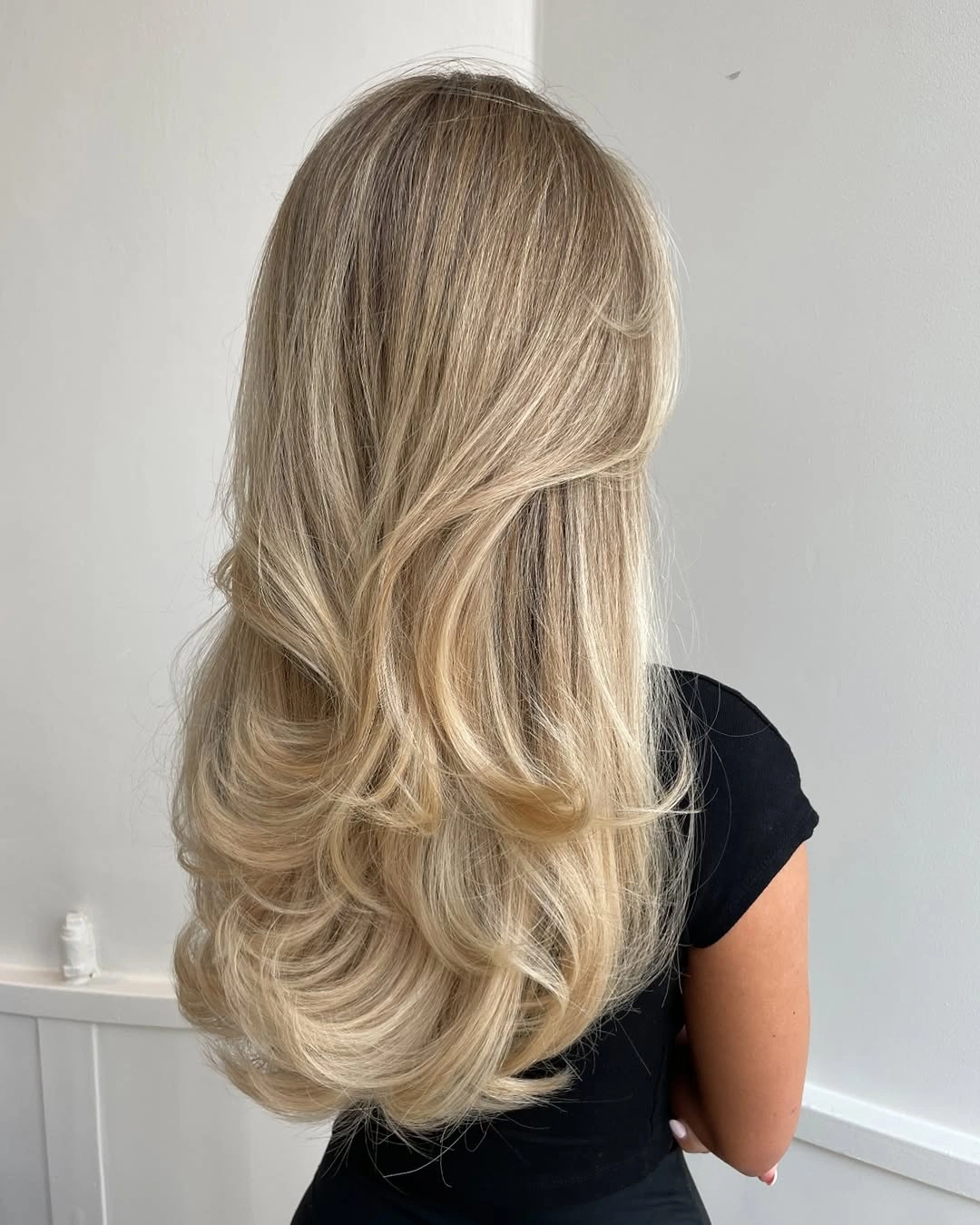 Back view of long dimensional blonde hair with curled layers