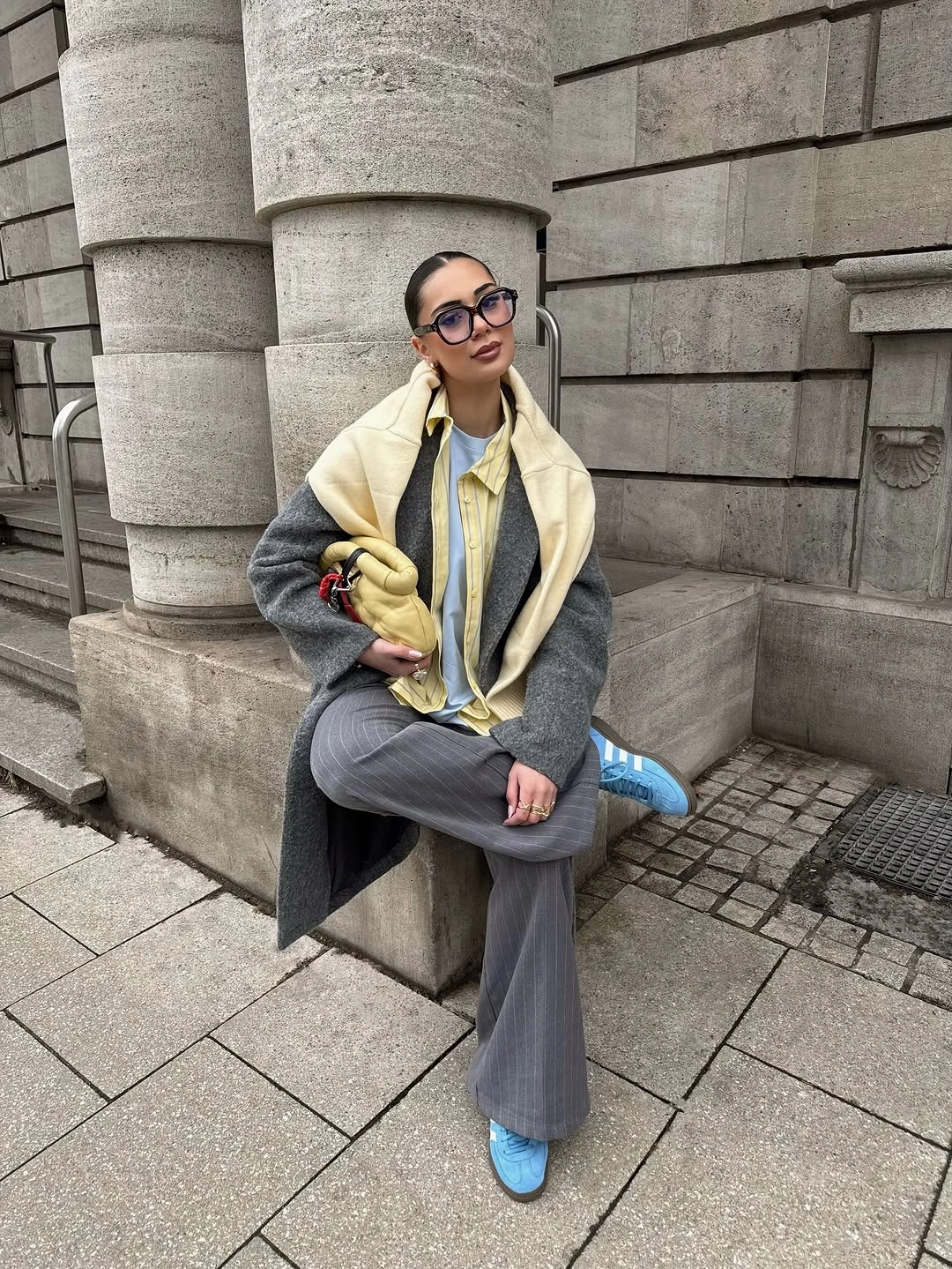 Gray coat pinstriped trousers yellow shirt and blue sneakers