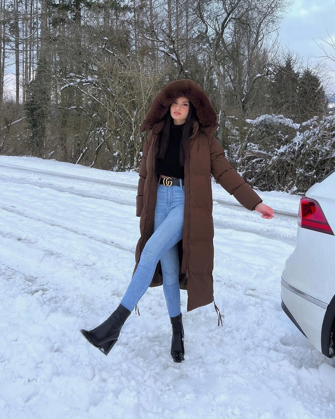 Brown hooded coat black top pale jeans and pointed boots
