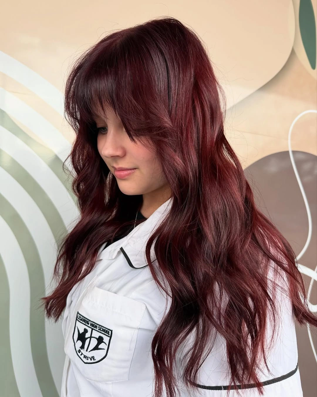 Long burgundy-plum waves with full bangs