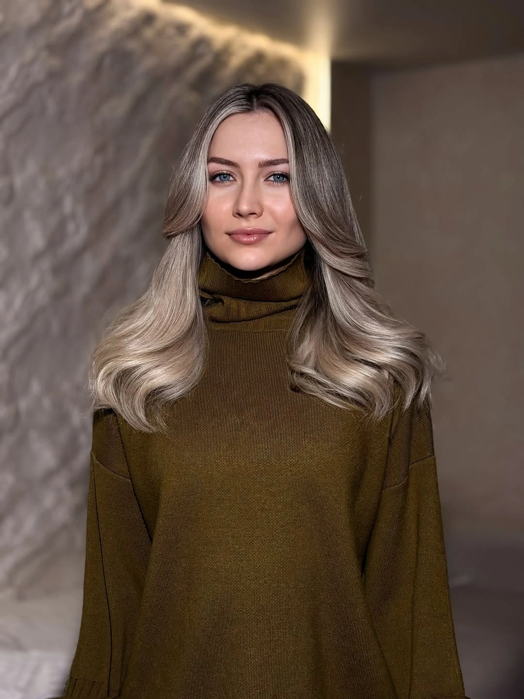 Long taupe-blonde waves with darker upper depth and pale ends