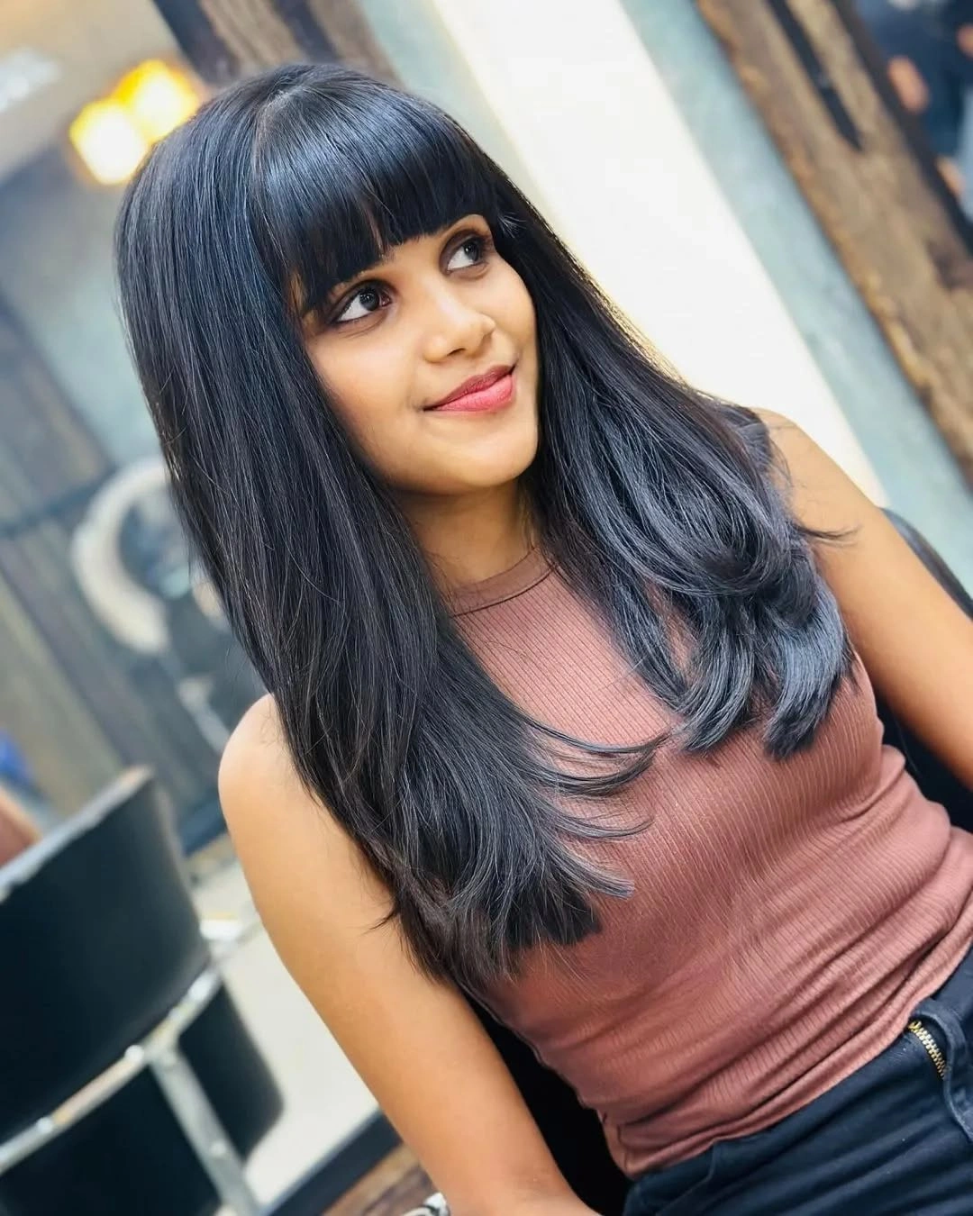 Long dark hair with full bangs and curved ends