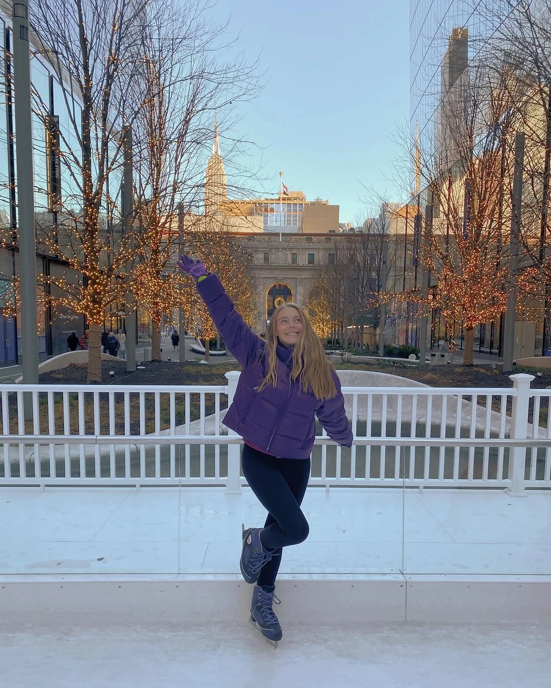 Woman in purple puffer, dark leggings, and skates on ice