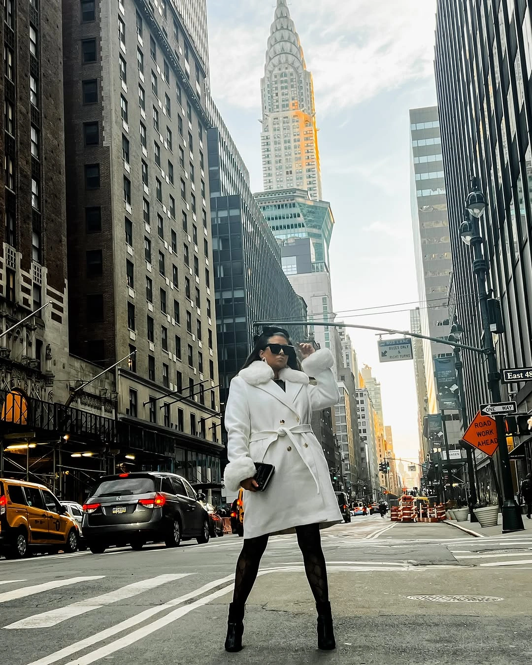 Woman in white belted coat with black tights and boots