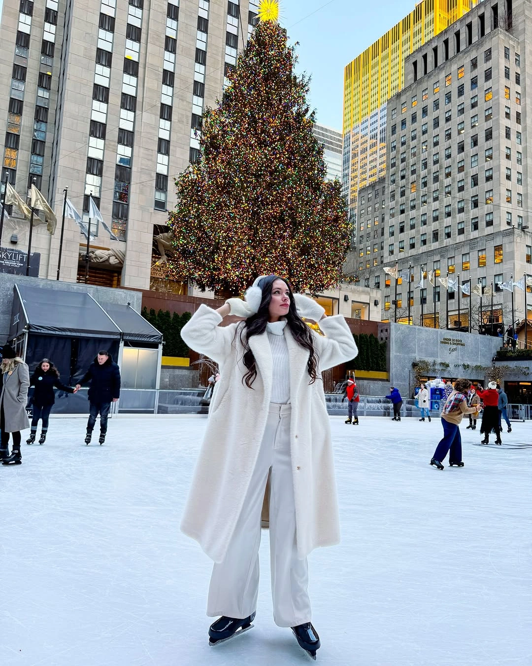 Woman in long white coat and pale trousers on ice