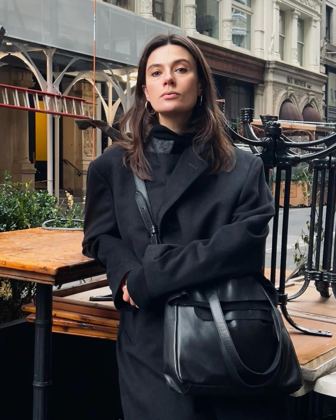 Woman in oversized black blazer with large black shoulder bag