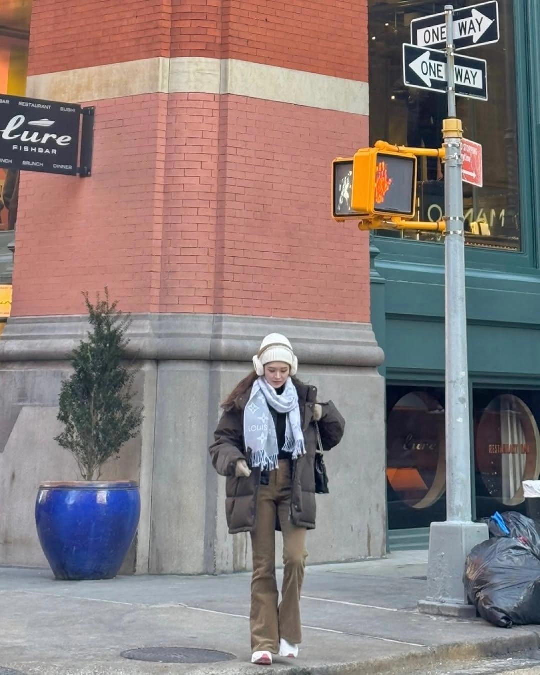 Woman in brown padded jacket with pale scarf and hat