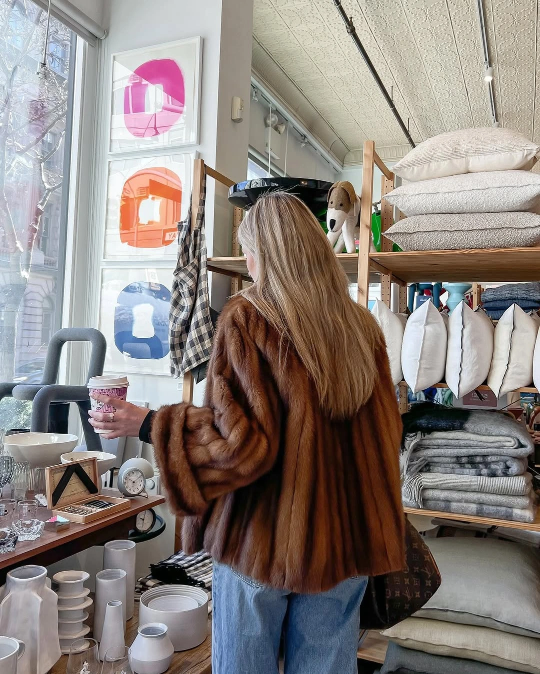 Woman in brown fur-like jacket and loose light-blue jeans