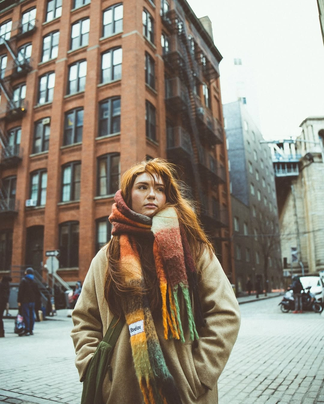Woman in beige coat with oversized multicolor striped scarf