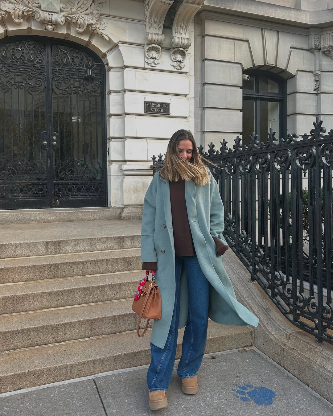 Woman in pale blue coat with jeans and tan accessories