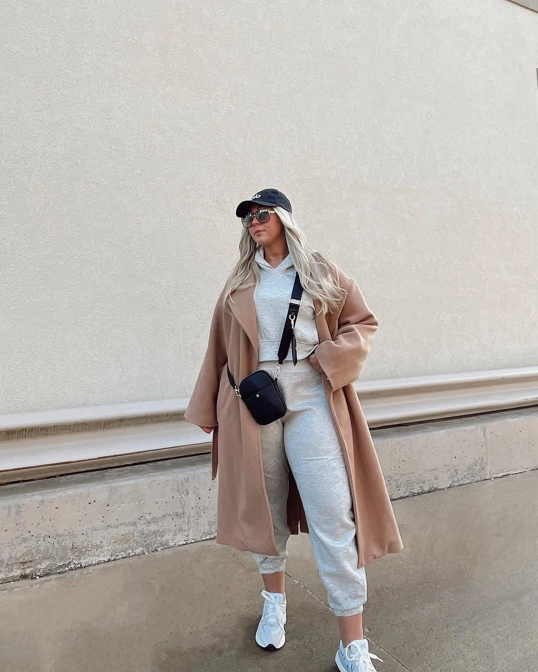 Camel coat over gray hoodie and joggers with white sneakers