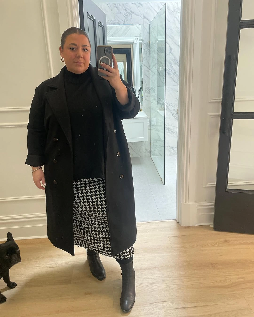 Long black coat with turtleneck, patterned skirt, and ankle boots