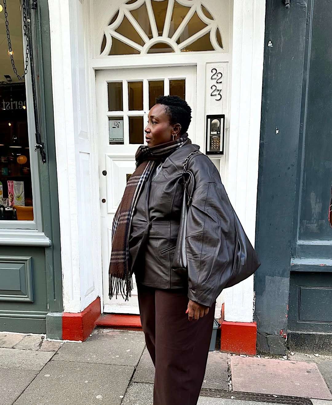 Dark leather-look jacket with brown scarf and large shoulder bag