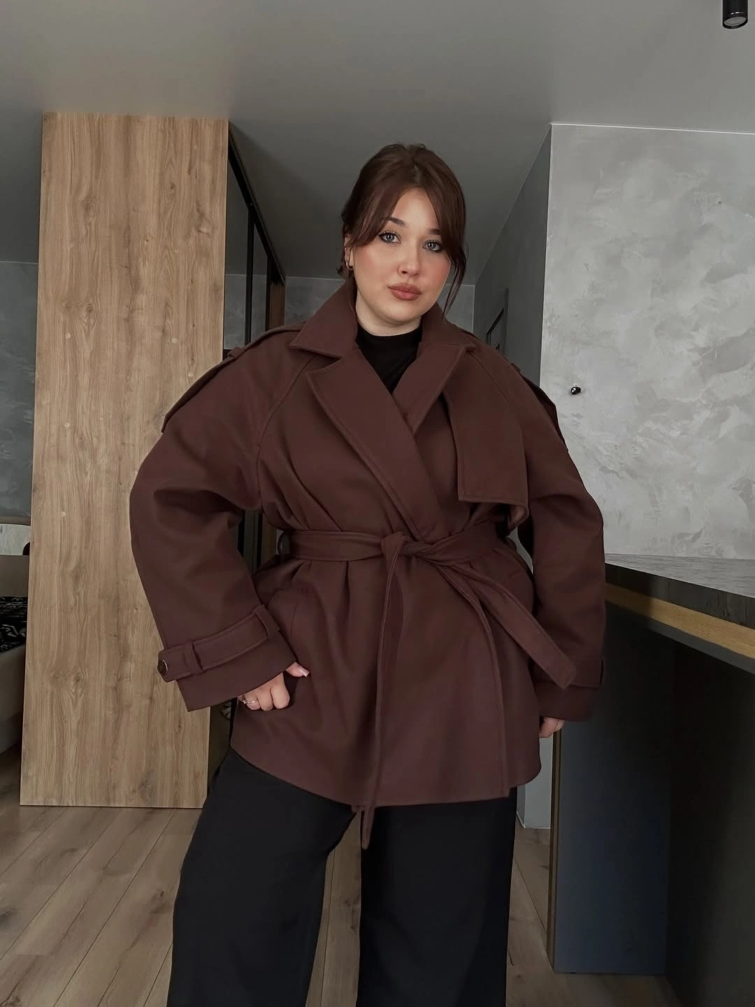 Brown belted wrap-style coat over black top and pants
