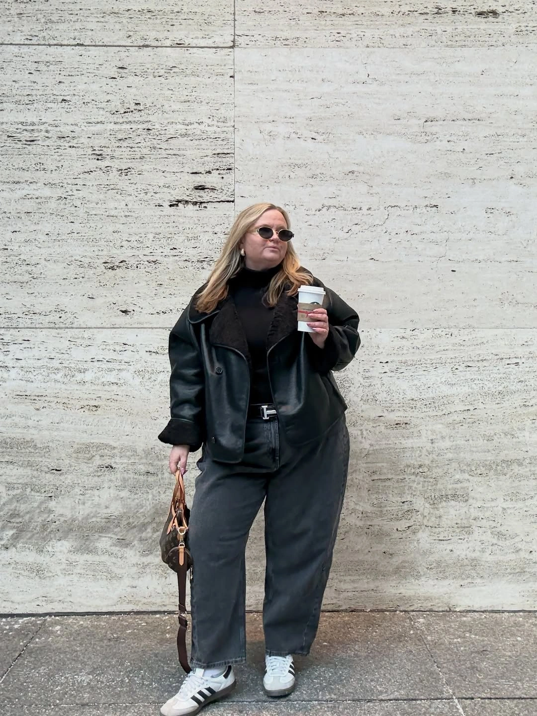 Black leather-look jacket with dark jeans and white sneakers