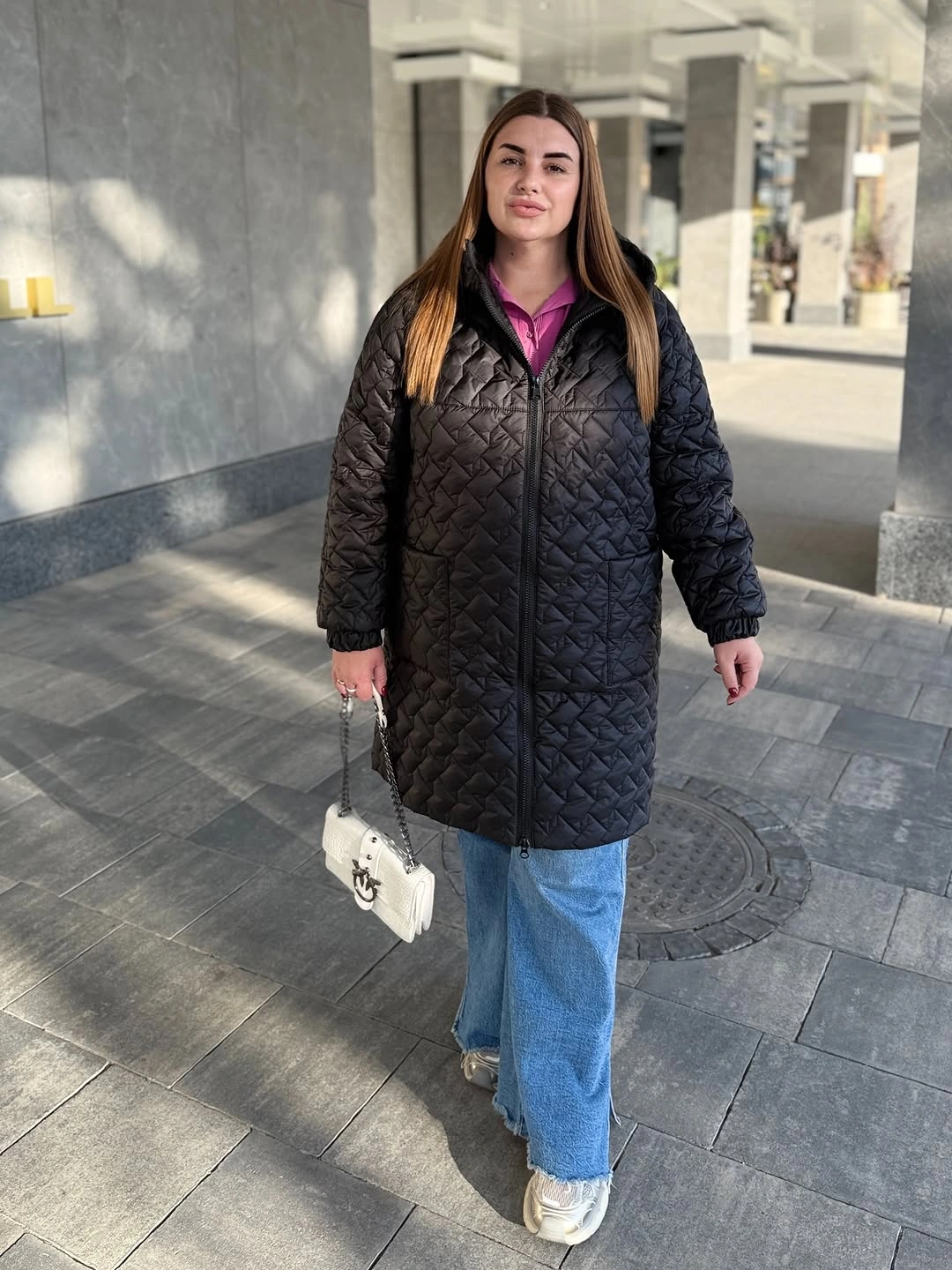 Black quilted coat over pink hoodie and wide jeans