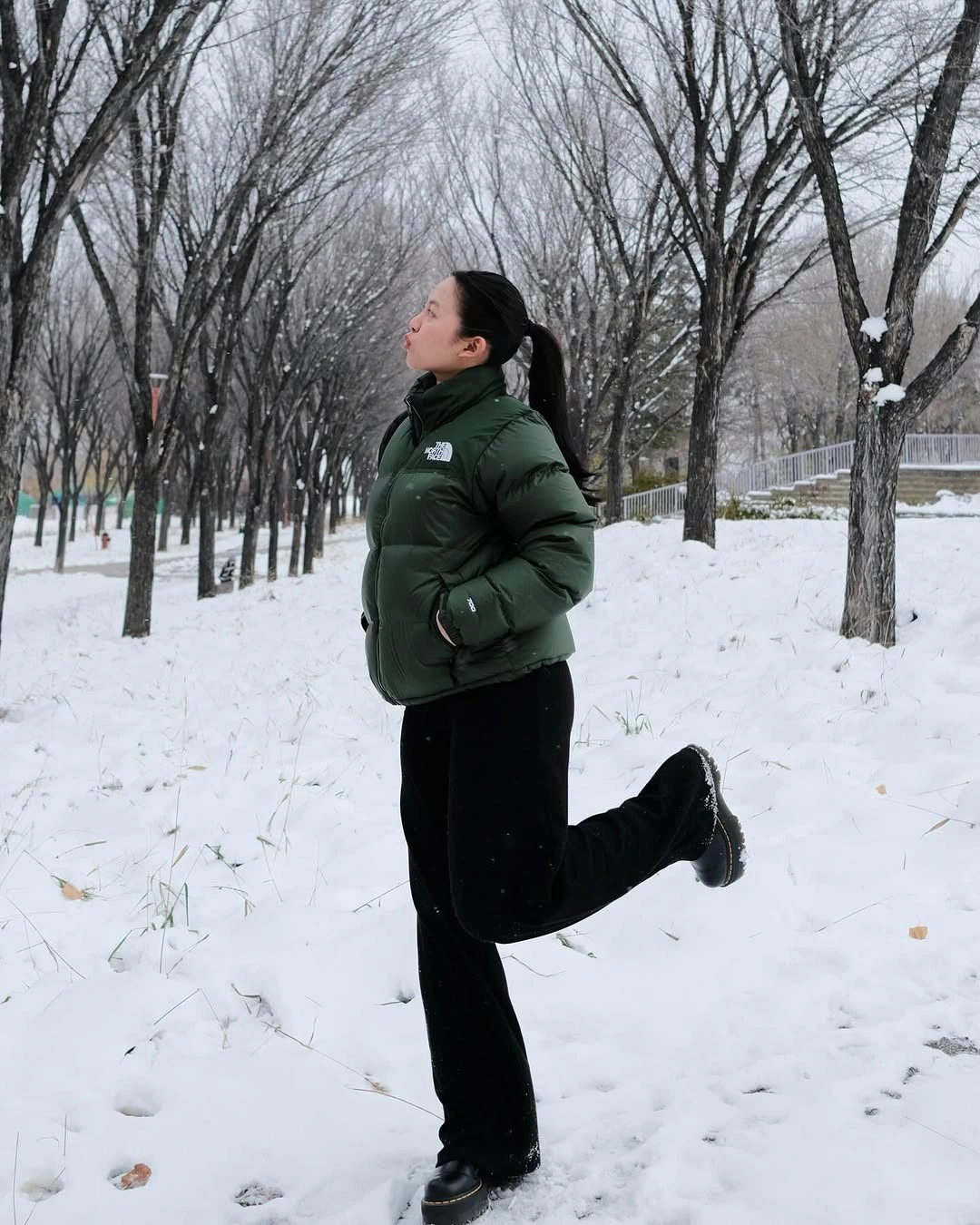 deep green quilted puffer jacket with black pants and chunky black shoes