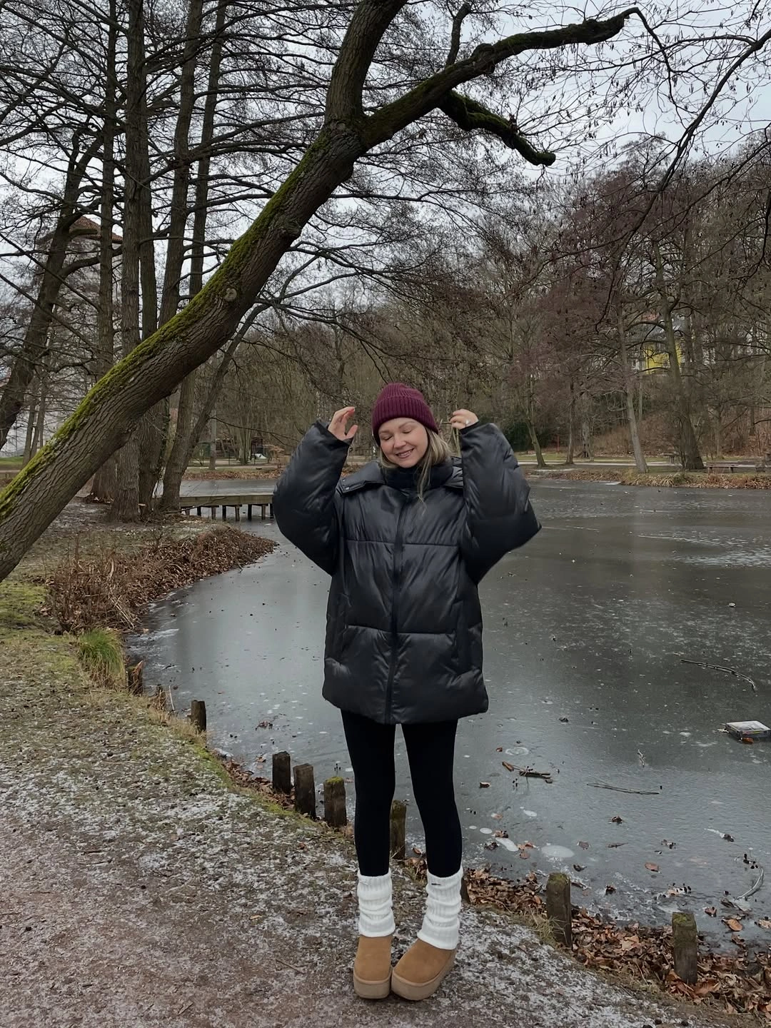 black mid-length puffer with burgundy beanie black leggings white socks and tan ankle boots