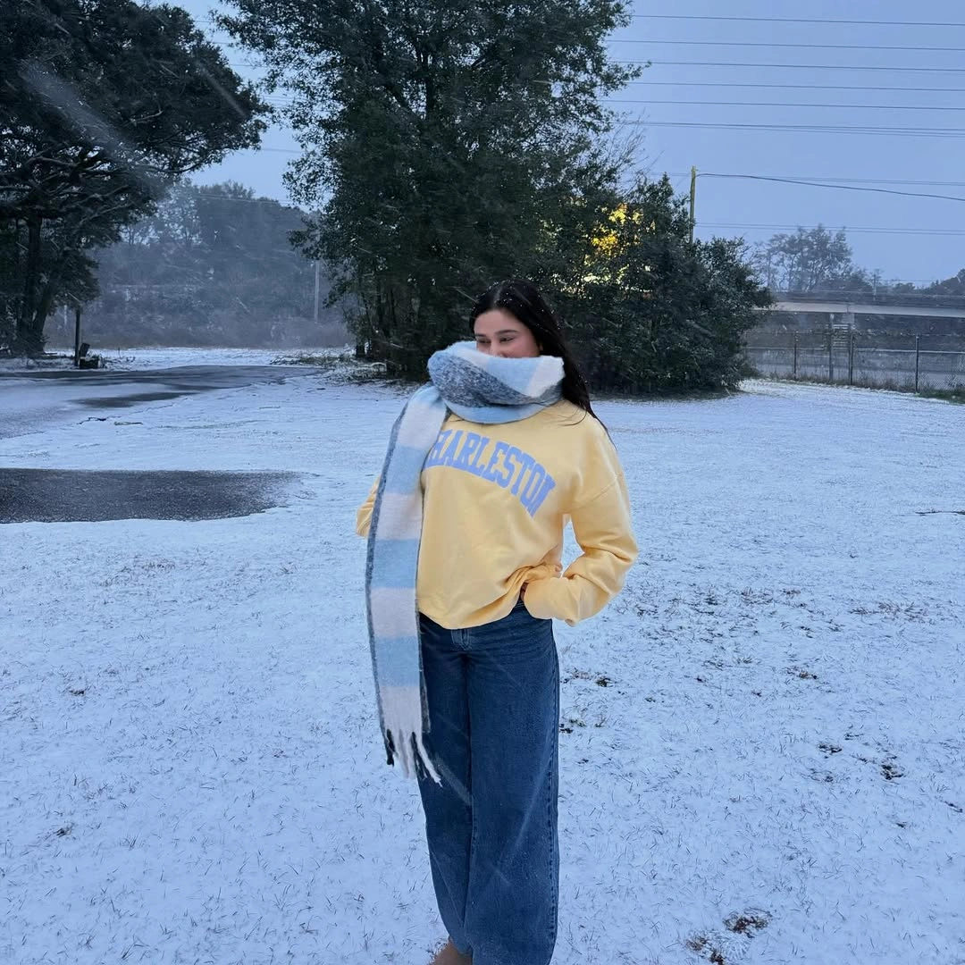pale yellow sweatshirt with wide blue jeans and long striped scarf