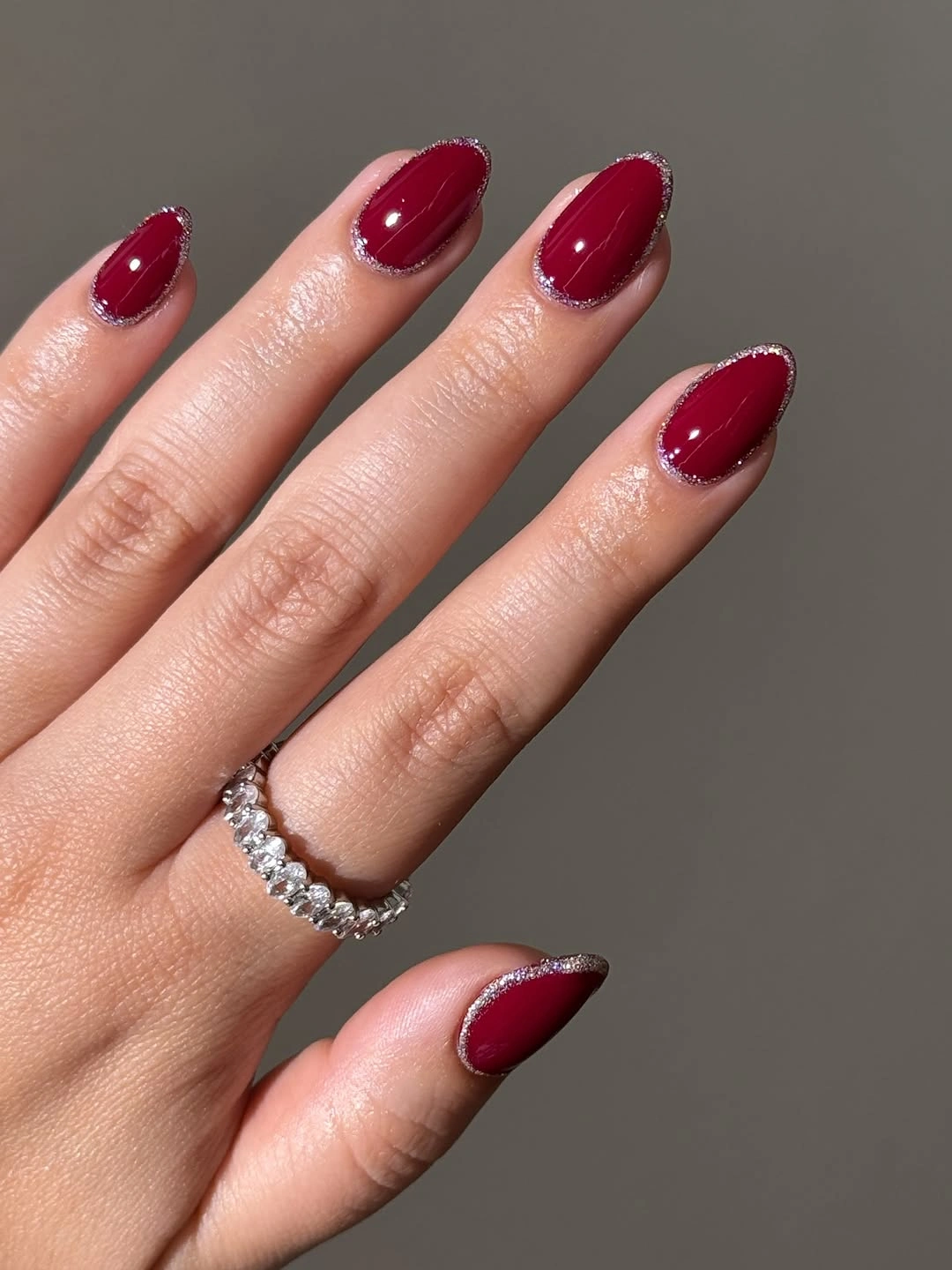 Short burgundy almond nails with thin silver glitter edging