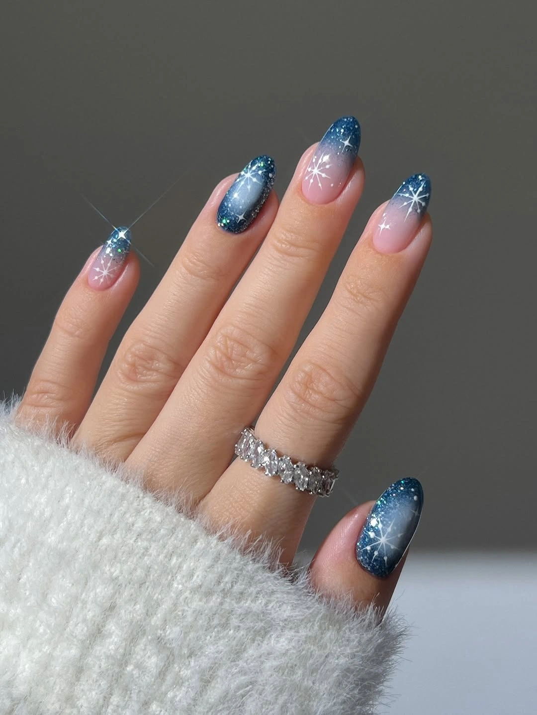 Short almond nails with blue glitter tips and white starbursts
