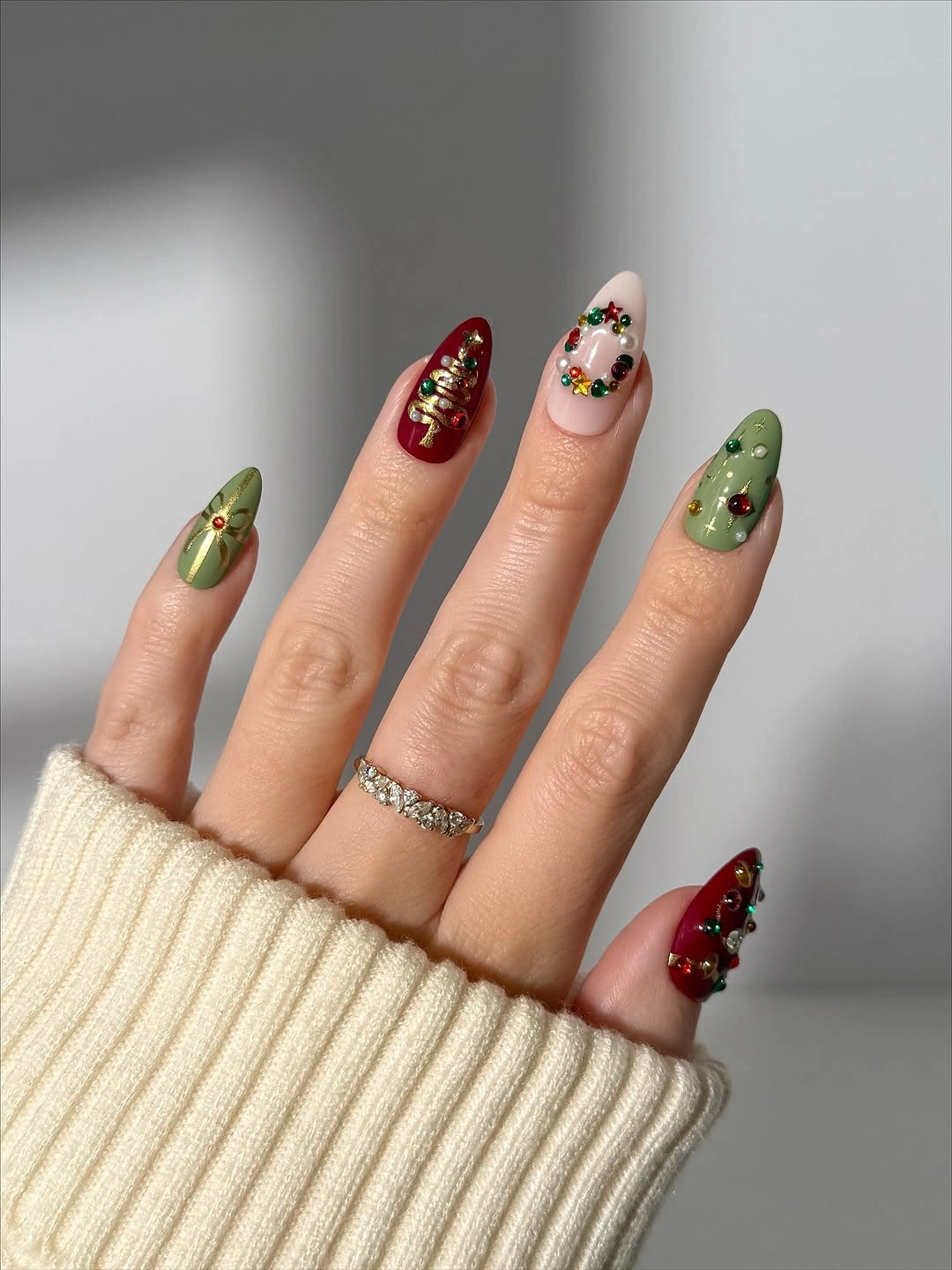 Almond nails with red, green, nude, and jewel-like holiday details