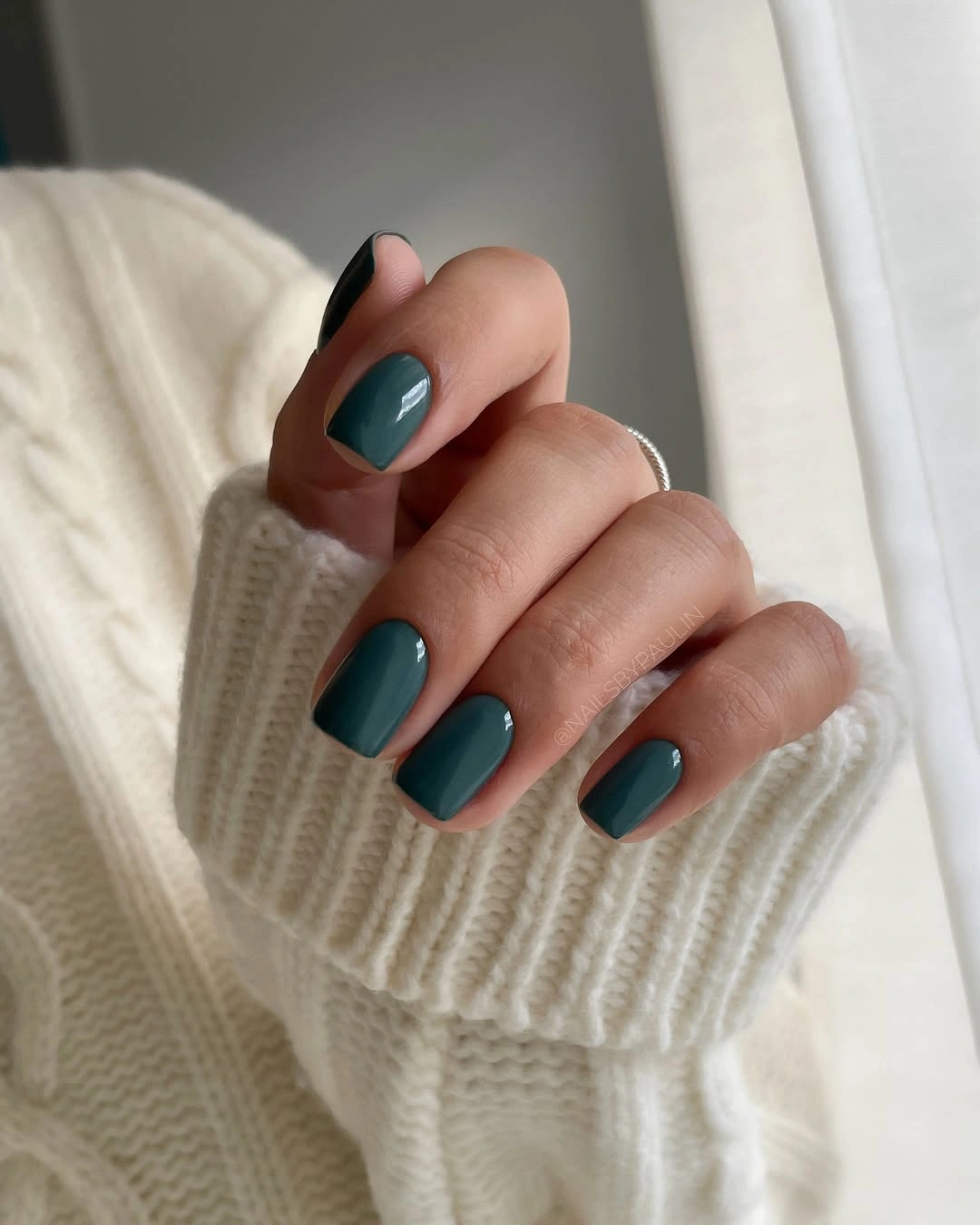 Very short rounded-square teal nails with one dark accent