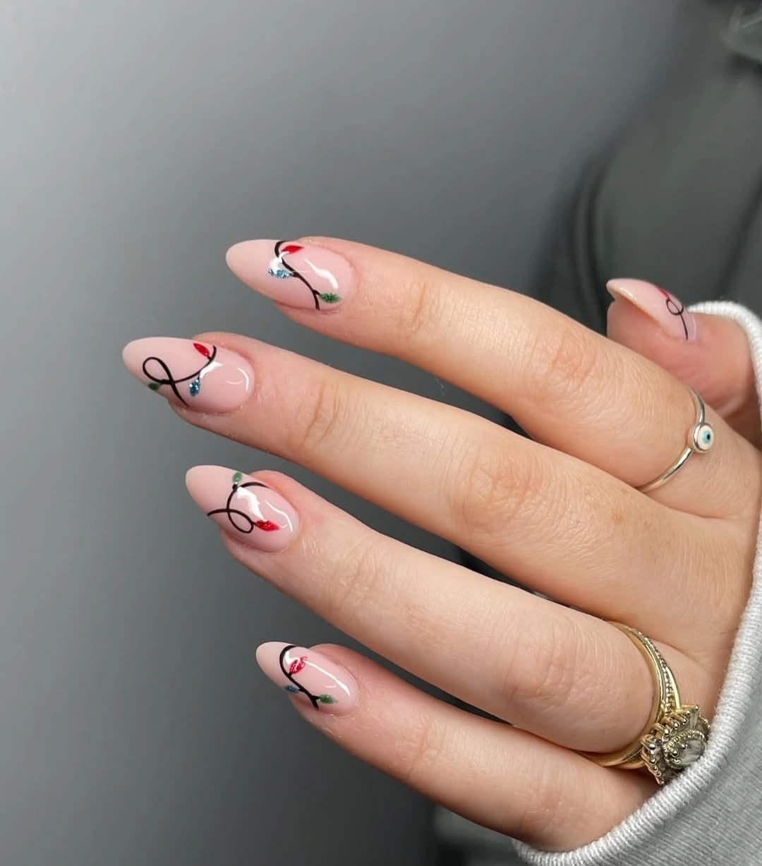 Short nude-pink almond nails with black loops and colored accents
