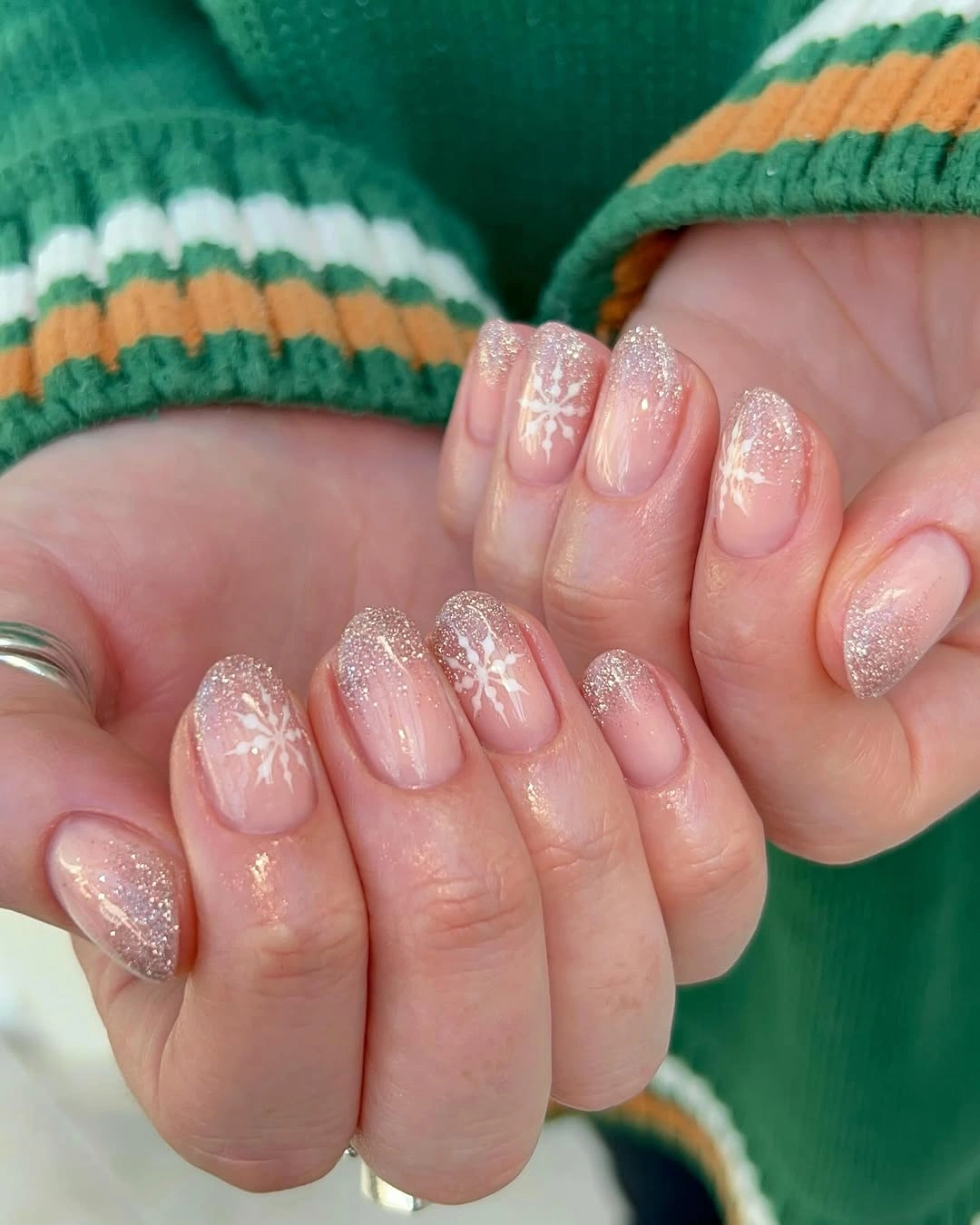 Short pink oval nails with glitter tips and white snowflakes